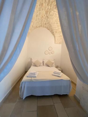 una camera da letto con un letto bianco con tende blu di Sav40 a Ostuni