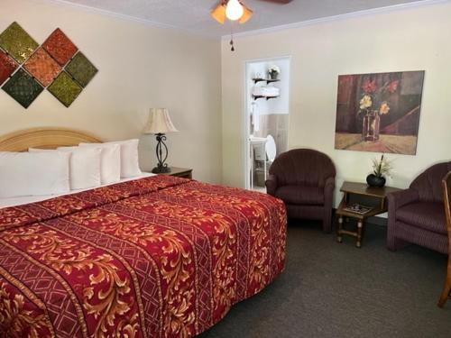 une chambre d'hôtel avec un lit et deux chaises dans l'établissement Rolling Brook Inn, à Maggie Valley