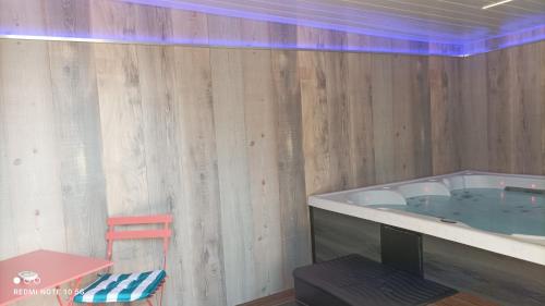 a room with a tub with a table and a chair at Le jardin de Chouchat in Gavray