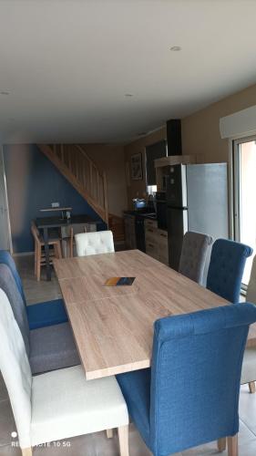 une cuisine avec une table en bois et des chaises bleues dans l'établissement Le jardin de Chouchat, à Gavray