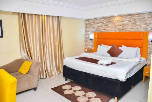 a bedroom with a large bed and a chair at Shamrockmanor(TheResidence) in Benin City