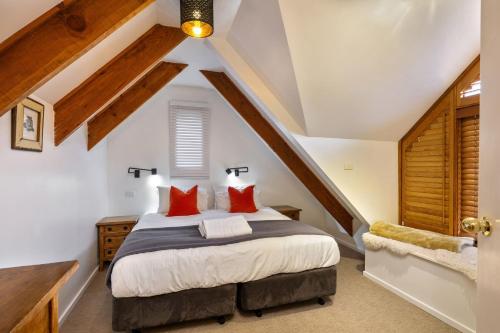 a bedroom with a large bed with red pillows at Crackenback Castle free standing chalet with fire place in Thredbo