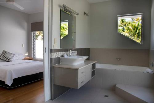 a bathroom with a sink and a bed and a mirror at 2/24 Donkin - Luxury - Absolute Beachfront in Mission Beach