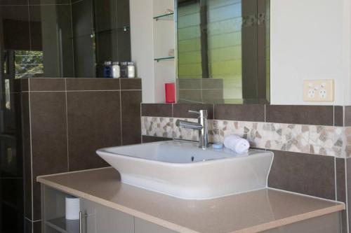 a bathroom with a white sink and a mirror at 2/24 Donkin - Luxury - Absolute Beachfront in Mission Beach
