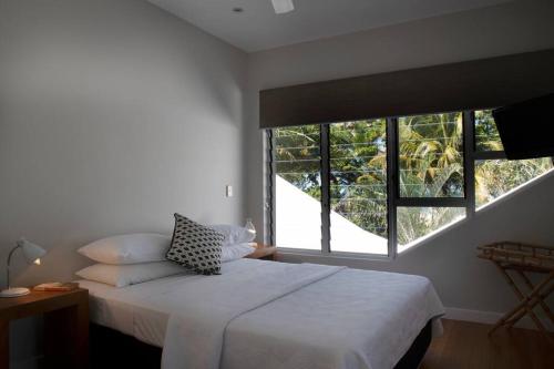 a bedroom with a white bed and two windows at 2/24 Donkin - Luxury - Absolute Beachfront in Mission Beach