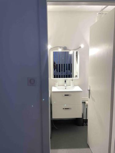 une salle de bain blanche avec un lavabo et un miroir dans l'établissement Grand Studio avec Jacuzzi, à Strasbourg