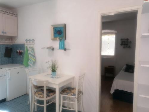 a small kitchen with a white table and chairs at Apartments by the sea Milna, Vis - 8490 in Vis