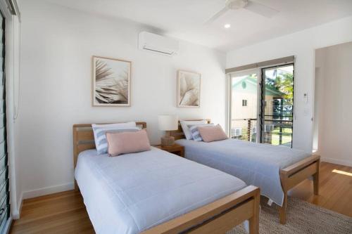 two beds in a room with a window at Nikatara - Mission Beach - 3 Bedroom Town House in Mission Beach