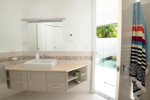 La salle de bains est pourvue d'un lavabo, d'un miroir et d'une douche. dans l'établissement Nikatara - Mission Beach - 3 Bedroom Town House, à Mission Beach