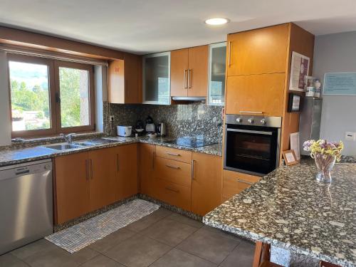 a large kitchen with wooden cabinets and a window at Casa da Lage - Vistas rio - Gerês in Geres