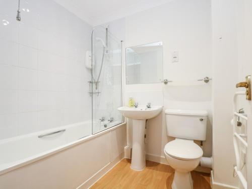 a white bathroom with a toilet and a sink at Rosemary Cottage in Falmouth