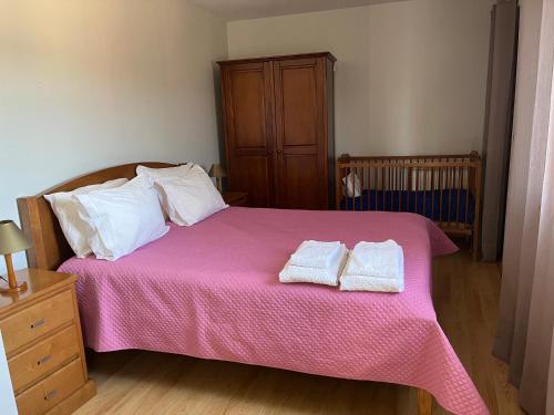 a bedroom with a pink bed with two towels on it at Casa da Lage - Gerês - Piscina privada in Geres