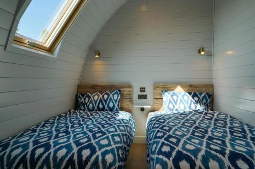 two beds in a small room with a window at King's Lynn Caravan & Camping Park in Kings Lynn