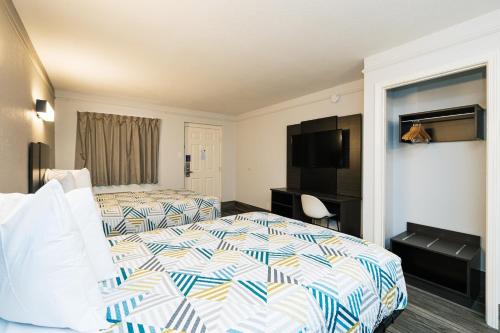 a hotel room with two beds and a flat screen tv at Motel 6-Baytown, TX - Garth Rd in Baytown