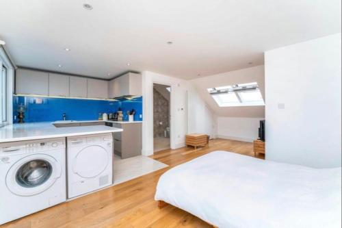 a room with a bed and a kitchen with a washing machine at Large, light & airy 4 bedroom home on quiet road in London