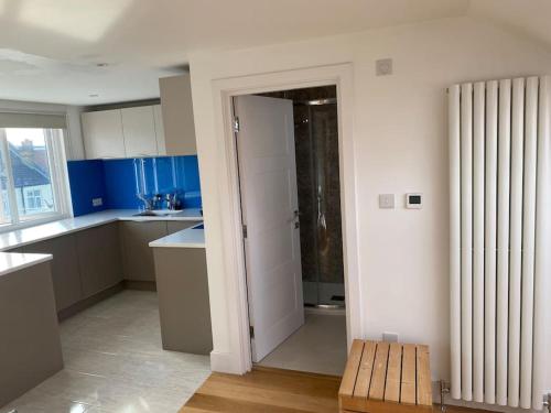 una cocina con paredes azules y blancas y un banco de madera en Large, light & airy 4 bedroom home on quiet road, en Londres