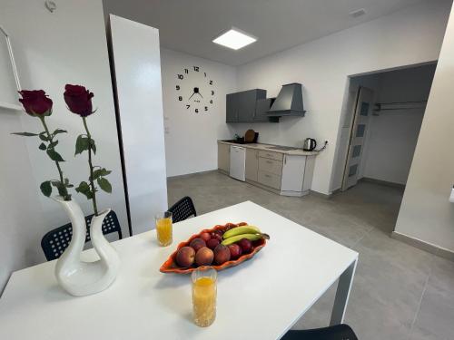 a table with a bowl of fruit and a vase with flowers at Apartament I w Centrum - Winda - 50 metrów od Starego Rynku in Kościerzyna