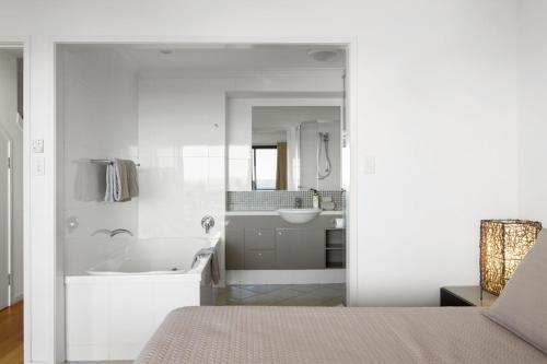 La salle de bains blanche est pourvue d'une baignoire et d'un lavabo. dans l'établissement Shorelines 27 Ocean View Buggy Transfers BBQ, à Île Hamilton