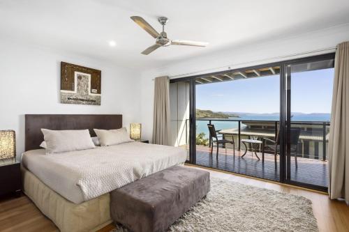 a bedroom with a bed and a balcony with a view at Shorelines 27 Ocean View Buggy Transfers BBQ in Hamilton Island