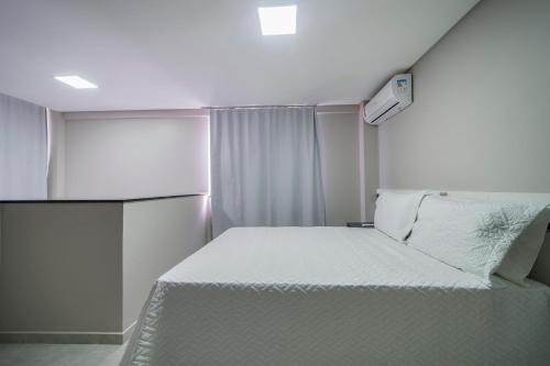 a small bedroom with a white bed and a light at Flórida Premium in Bombinhas