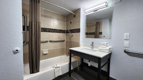 a bathroom with a sink and a tub and a mirror at Motel 6-Baytown, TX - Garth Rd in Baytown