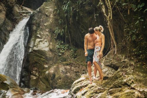 a man and a woman standing on rocks near a waterfall at Terramia Estate in Minca