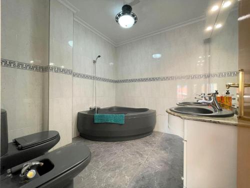 La salle de bains est pourvue d'une baignoire, de deux lavabos et de toilettes. dans l'établissement Spacious apartment in Los Alcazares with balcony, à Los Alcázares