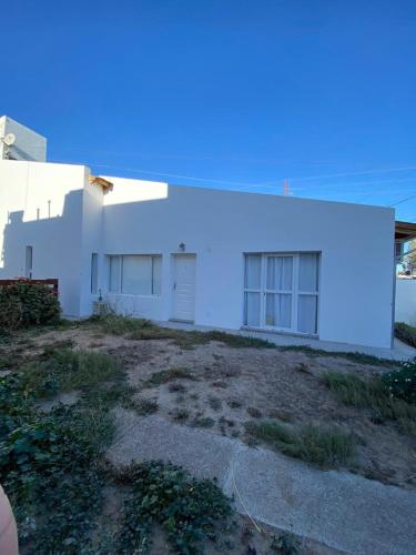a white house with a yard in front of it at La alegre! Hermosa casa centrica y cerca del mar in Puerto Madryn