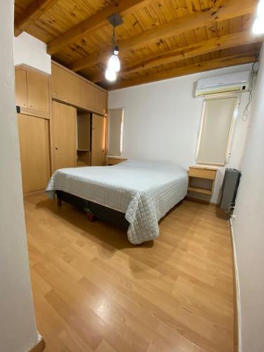 a bedroom with a bed and a wooden floor at La alegre! Hermosa casa centrica y cerca del mar in Puerto Madryn