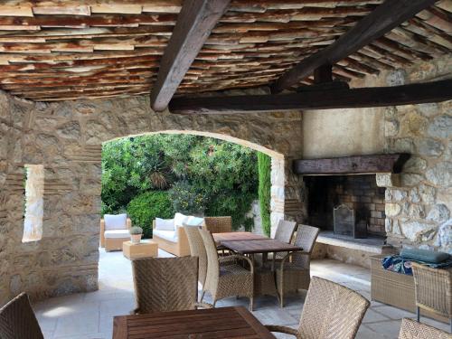 un patio avec une table, des chaises et une cheminée dans l'établissement Le Haut des Espinets, à Saint-Paul-de-Vence