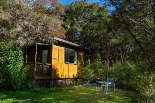 a yellow cabin with a table and chairs in the yard at Ao Marama Retreat in Collingwood