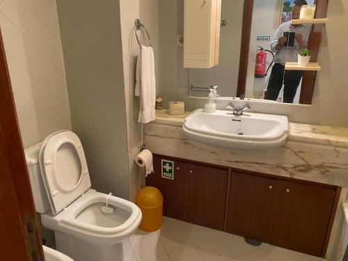 a bathroom with a sink and a toilet and a mirror at Painel da Caparica in Costa da Caparica