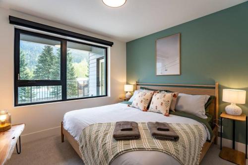 a bedroom with a bed with two towels on it at Revy Bliss - Dazzling Condo in the Mountains in Revelstoke