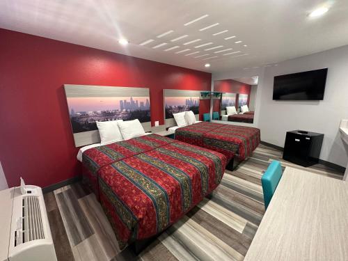 a hotel room with two beds and a flat screen tv at Sahara Inn - Los Angeles in Los Angeles