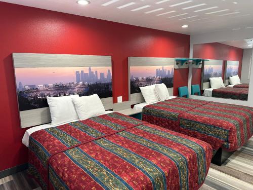 a hotel room with two beds with red walls at Sahara Inn - Los Angeles in Los Angeles