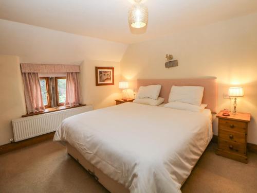 a bedroom with a large white bed and a window at Green Farm Cottage in Ashbourne
