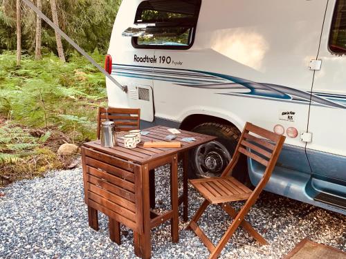 uma mesa e cadeiras em frente a uma caravana em Shady Van in the Woods em Gillies Bay