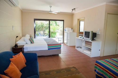 1 dormitorio con 1 cama, TV y sofá en Breeya - A great tropical escape. Sleeps 9, en Mission Beach