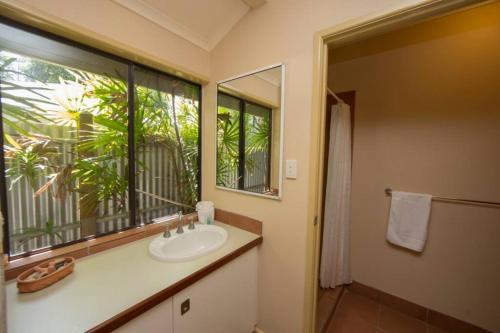 baño con lavabo, ventana y espejo en Breeya - A great tropical escape. Sleeps 9, en Mission Beach