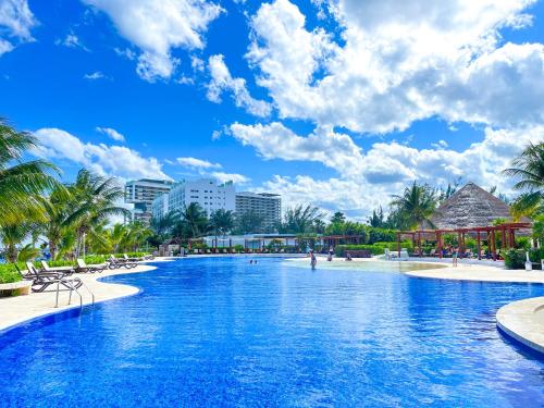 una piscina in un resort con palme e edifici di New Beachfront Luxury Apartments a Cancún