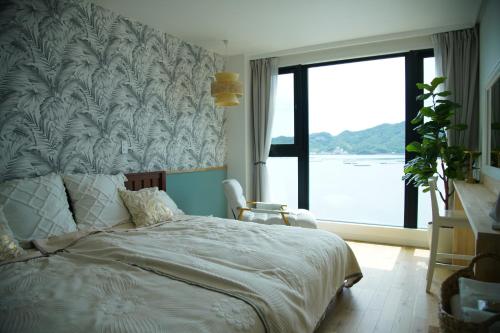 a bedroom with a bed and a large window at Villacation the Loose in Minamiawaji