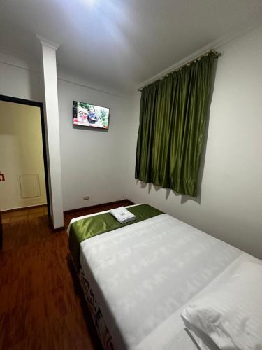 a room with two beds and a window with green curtains at Hotel Artistico in Bogotá