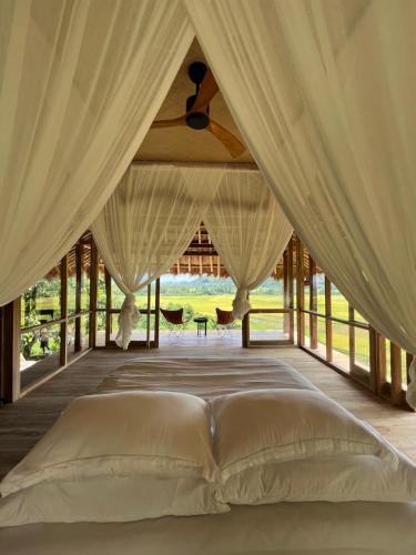 a bed in the middle of a room with curtains at Sumba Farm House in Sumba