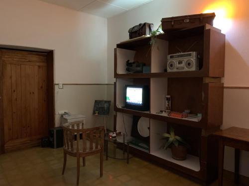 sala de estar con TV en un estante en Hostel Casa Doble V El Precio es por Persona en Ramallo