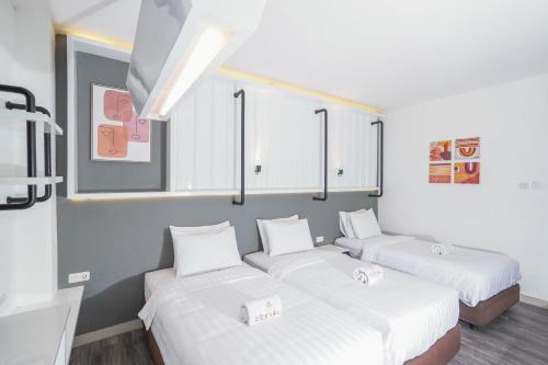 a room with three beds with white sheets at Istanaku in Manado