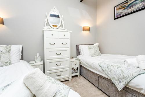 a bedroom with two beds and a mirror at Nurse's Cottage in Alnwick