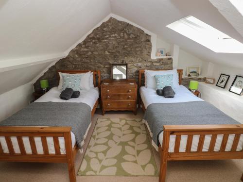 a attic room with two beds and a stone wall at Briar Cottage in Neyland