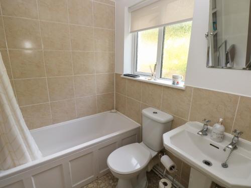 a bathroom with a toilet and a tub and a sink at Briar Cottage in Neyland