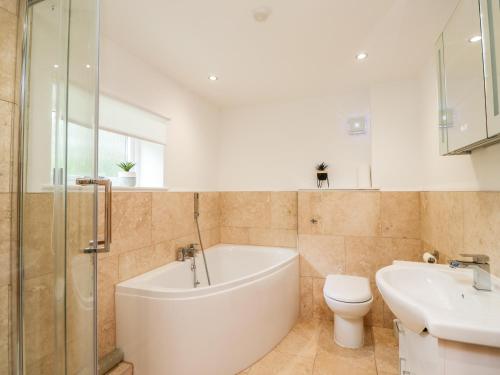 a bathroom with a tub and a toilet and a sink at Dunstanburgh View in Embleton