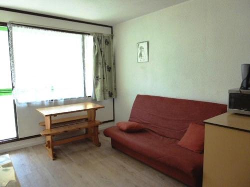 un salon avec un canapé rouge et une table dans l'établissement Studio cosy pour 4 pers. à deux pas des pistes avec kitchenette et loggia - Arette - FR-1-602-113, à Arette